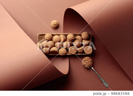 Tasty chocolate truffles and spoon with cocoa powder. 98683566