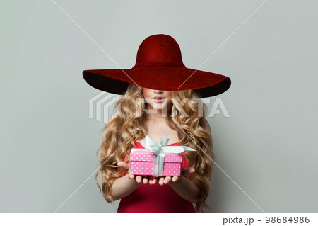 Lovely woman in wide red broad brim hat with gift on white background Lovely woman in wide red broad brim hat with gift on white background 98684986