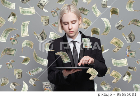 Concept photo of a businesswoman with tablet standing under money rain. 98685081