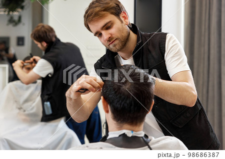 hairdresser does haircut for caucasian bearded man 98686387