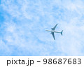 青空の中を飛ぶ飛行機 98687683