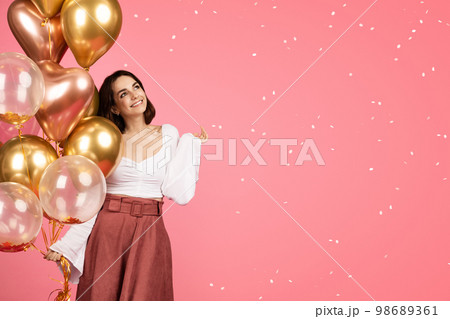 Happy dreamy young caucasian woman with many inflatable balloons enjoy confetti 98689361