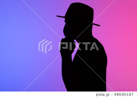 Silhouette african american man in hat with medical mask against the colourful neon background copy space Silhouette african american man in hat with medical mask against the colourful neon background copy space 98690187