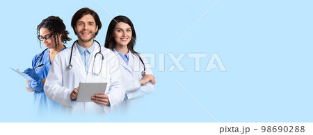 Friendly smiling multiethnic doctors posing on blue, holding digital tablet 98690288