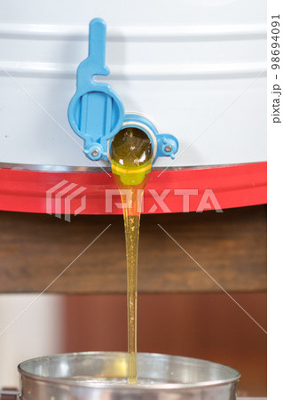 Drop of bee honey drip from hexagonal honeycombs Drop of bee honey drip from hexagonal honeycombs 98694091