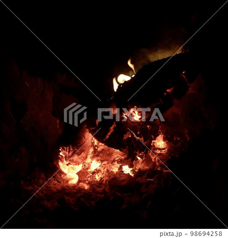 Beautiful flame brown wood dark black coal on bright yellow fire inside metal brazier 98694258