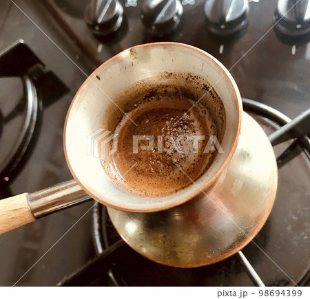 Barista preparing hot tasty drink from copper turk 98694399