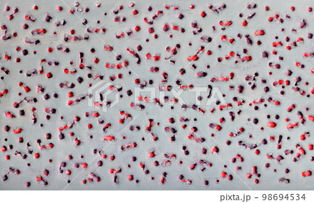 Abstract pattern texture with pierced ragged holes on a gray background on an underlay of red. 98694534
