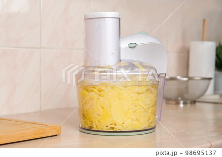 Potatoes cut into thin slices in food processor 98695137