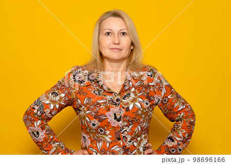 Smiling woman in patterned dress posing isolated on yellow wall background studio portrait. People emotions lifestyle concept. Mock up copy space. Standing with arms akimbo on the waist 98696166