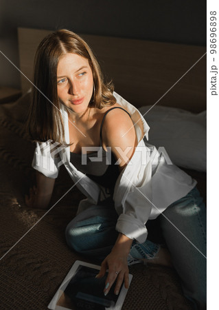 Portrait of young beautiful woman near window with shadow with digital tablet. Morning spring aesthetics and social networks digital technologies concept 98696898