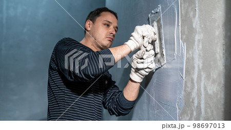 man applies insulation to a bathroom wall man applies insulation to a bathroom wall 98697013