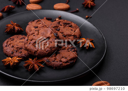 Delicious chocolate cookies with nuts on a black ceramic plate Delicious chocolate cookies with nuts on a black ceramic plate 98697210