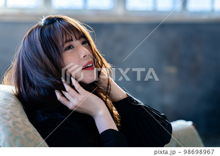 シックな部屋のソファで寛ぐクールな女性 98698967
