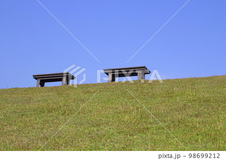 Public chairs on grass and blue sky background Public chairs on grass and blue sky background 98699212