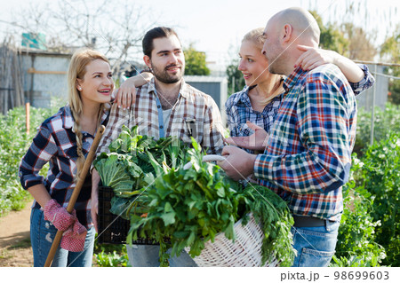 Happy farmers posing with a harvest of vegetables 98699603
