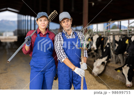 Portrait of man and woman farmers on dairy farm Portrait of man and woman farmers on dairy farm 98699755