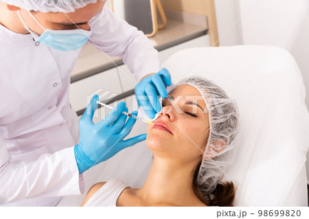 Woman receiving rejuvenating facial injections 98699820