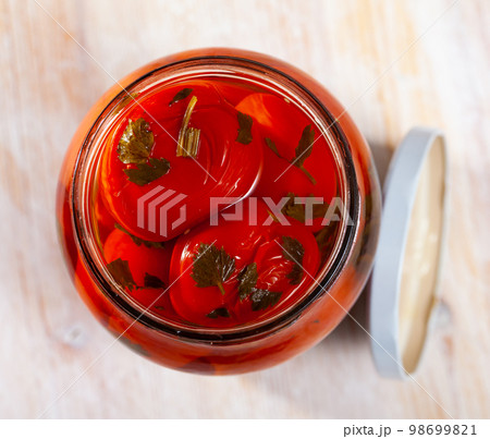 Tomatoes marinated in jars on a wooden table 98699821