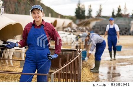 Young woman farmer giving water to calves on farm Young woman farmer giving water to calves on farm 98699941