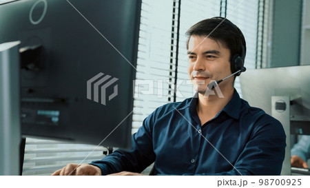 Young competent asian male call center agent working in the office. 98700925