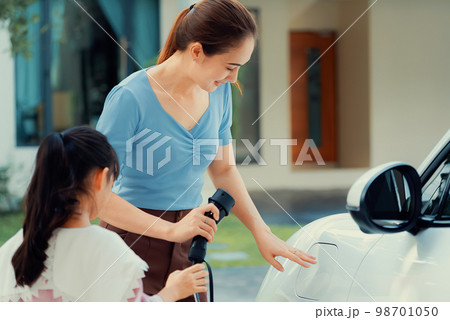 Progressive lifestyle of mother and daughter with EV car and charging station. Progressive lifestyle of mother and daughter with EV car and charging station. 98701050