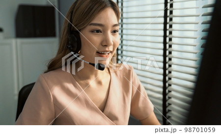 Competent female operator working on computer and while talking with clients. 98701059