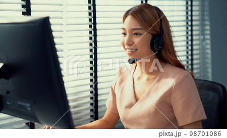 Competent female operator working on computer and while talking with clients. 98701086