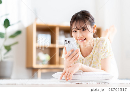 リビングでスマホを操作する若い女性。 リビングでスマホを操作する若い女性。 98703517