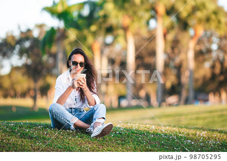 Young woman using mobile phone outdoor in the park 98705295