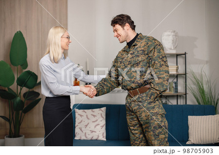 Soldier and psychiatrist standing in room after therapy session. Man wearing military uniform. Male warrior with ptds shaking hand of psychiatrist. 98705903