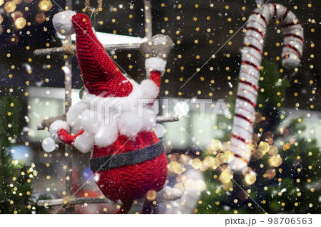 On a Christmas background, a toy santa claus climbs a rope ladder against a background of golden bokeh. 98706563