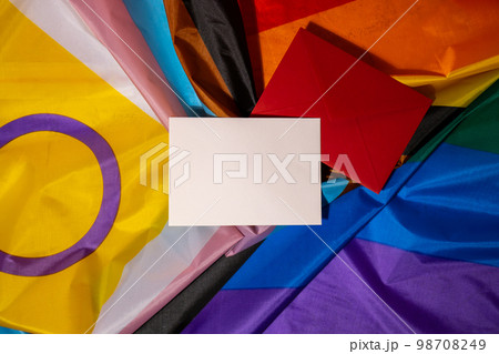Empty paper blank on Rainbow LGBTQIA flag made from silk material. Mock up template copy space for your text. Symbol of LGBTQ pride month. Equal rights. Peace and freedom. Support LGBTQIA community 98708249