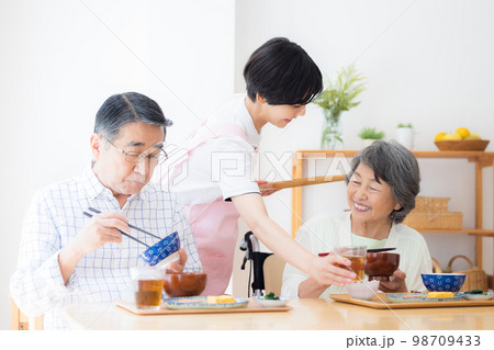 介護　ご飯を食べるシニアと介護士 98709433
