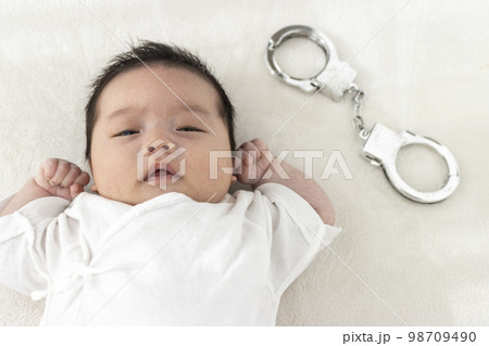 起きている赤ちゃんと玩具の手錠（0歳1か月、日本人、男の子） 98709490
