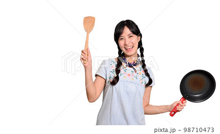 Portrait of beautiful young asian woman wear denim dress with black pan and spatula on white isolated background 98710473