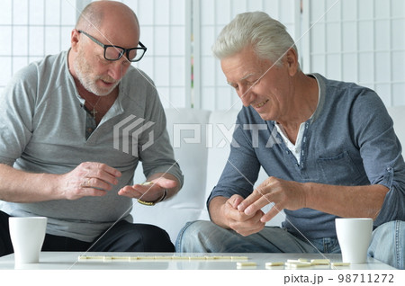 Two old men sitting at table and playing domino Two old men sitting at table and playing domino 98711272