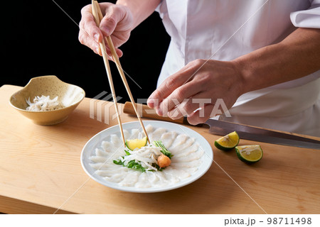 とらふぐの薄造りを盛り付ける板前 98711498