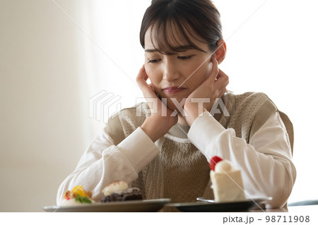 ケーキを食べたいけど我慢するダイエット中の女性 ケーキを食べたいけど我慢するダイエット中の女性 98711908