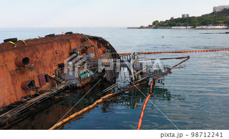 Overturned rusty oil tanker ship in the shallow water. Drowned sunken ship on its edge. Marine sea scape. Overturned rusty oil tanker ship in the shallow water. Drowned sunken ship on its edge. Marine sea scape. 98712241