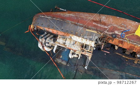 Aerial top view of overturned broken rusty oil tanker ship after the wreck. Drowned sunken ship in the shallow water. Aerial top view of overturned broken rusty oil tanker ship after the wreck. Drowned sunken ship in the shallow water. 98712267