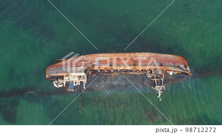 Overturned broken rusty oil tanker ship in the shallow water. Drowned ship after the wreck. 98712272