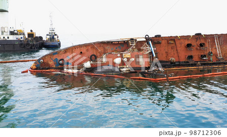 Close up of broken rusty oil tanker ship in the shallow water. Sunken drowned ship after the crash. 98712306