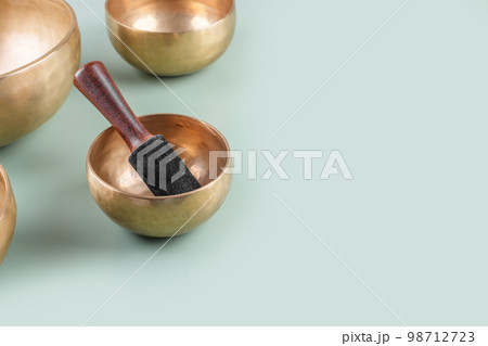 Tibetan singing bowls with sticks used during mantra meditations on green background, close up, copy space 98712723