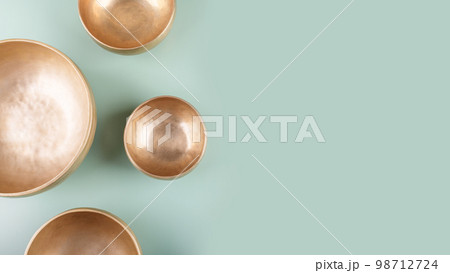 Tibetan singing bowls used during mantra meditations on green background, top view, copy space, web banner Tibetan singing bowls used during mantra meditations on green background, top view, copy space, web banner 98712724