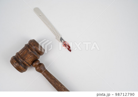 A scalpel covered in blood and a judge's wooden gavel. A scalpel covered in blood and a judge's wooden gavel. 98712790
