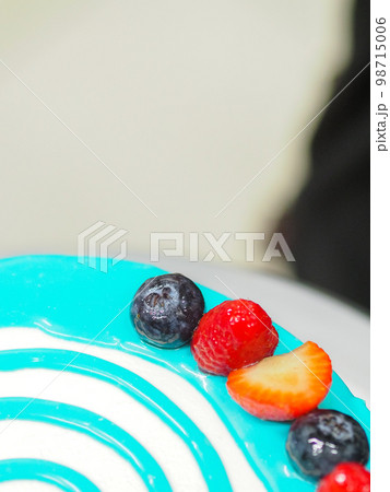 hand pastry chef designer topping a frosted white cake with pastel light blue drip filling bag 98715006