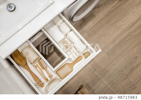 Bathroom under sink organizer drawers with neatly placed bath amenities and toiletries. Bathroom under sink organizer drawers with neatly placed bath amenities and toiletries. 98715963