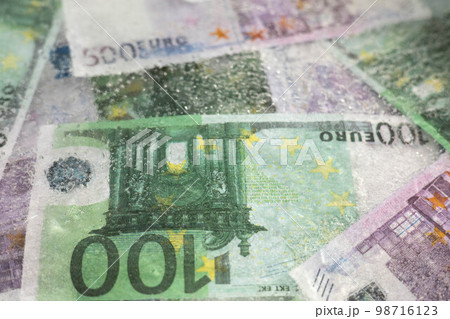 Blurred photo of one hundred and five hundred euros are defrosted in ice. The European cash currency is frozen. Blurred photo of one hundred and five hundred euros are defrosted in ice. The European cash currency is frozen. 98716123