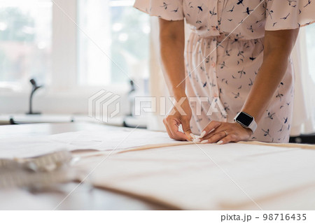 Happy dressmaker female use sewing patterns and measuring tape for creating fashion clothes 98716435